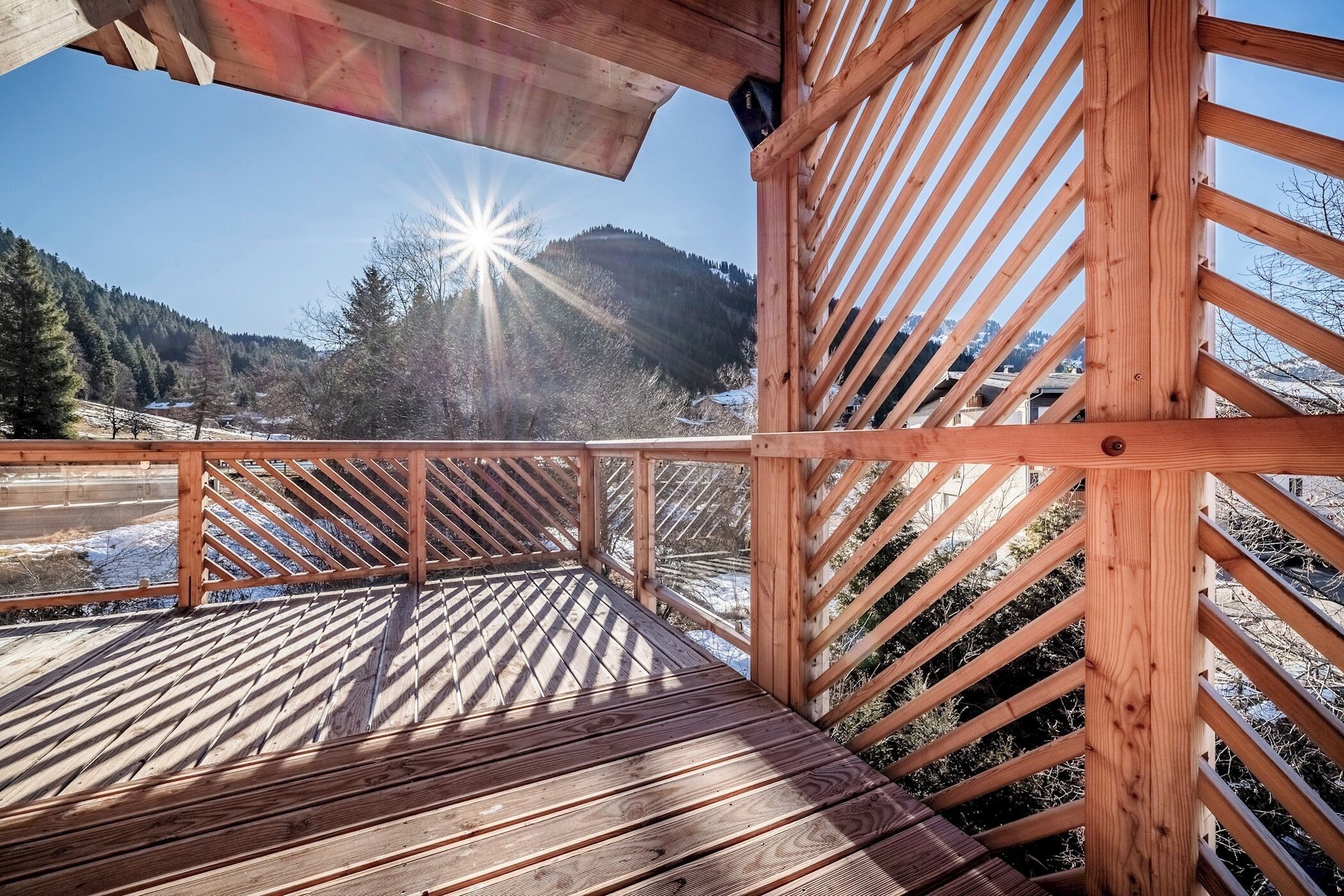 A wooden deck with a view of a snowy landscape and mountains.