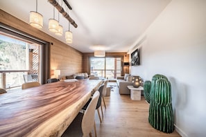 A spacious dining area with a long wooden table, multiple chairs, and hanging pendant lights. - Gabelac - alpine apartment with jacuzzi châtel (Châtel)
