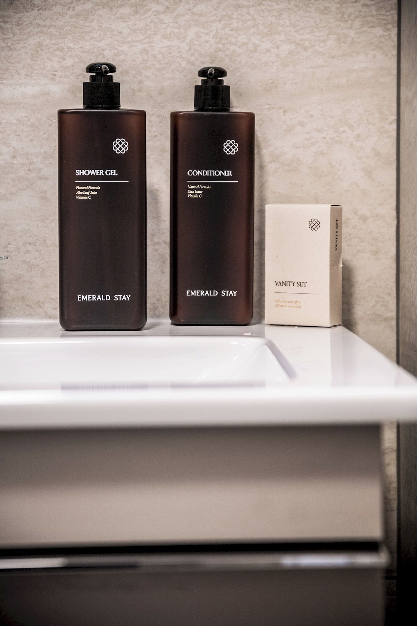 Twee flessen douchegel en conditioner op een witte plank, met een doos zeep van Vanity Set.