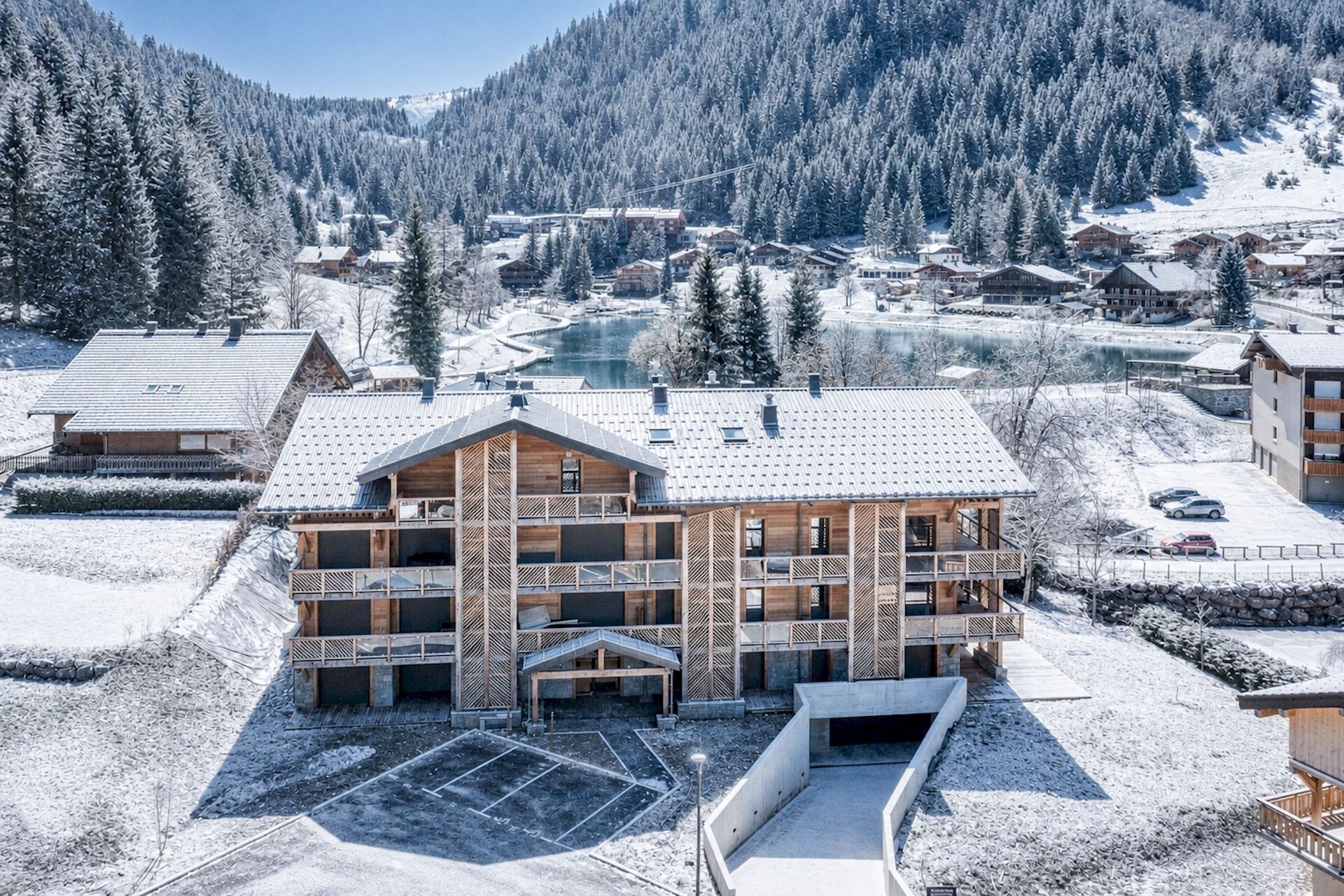 A multi-story building with a ski lift in the background, surrounded by snow-covered trees and a mountainous landscape.