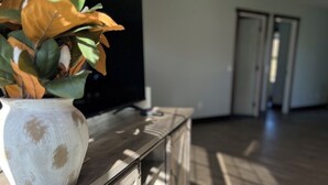 Ein Zimmer mit einem Holzkasten, einem Fernseher und einer Pflanze.