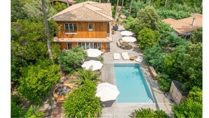 A wooden house with a tiled roof, surrounded by lush greenery and a swimming pool. - L'écrin du Ferret *Swimming pool *Air conditioning *Spa (Lège-Cap-Ferret)