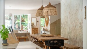 A modern dining area with a wooden table, woven chairs, and hanging rattan lamps. - L'écrin du Ferret *Swimming pool *Air conditioning *Spa (Lège-Cap-Ferret)