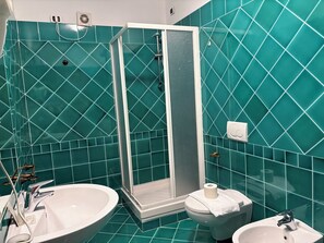 A bathroom with a shower enclosure, a sink, and a toilet.