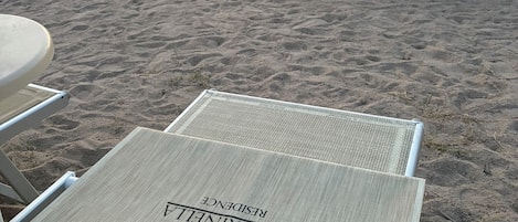 Una playa con tumbonas y sombrillas, vista despejada del agua y una montaña al fondo.