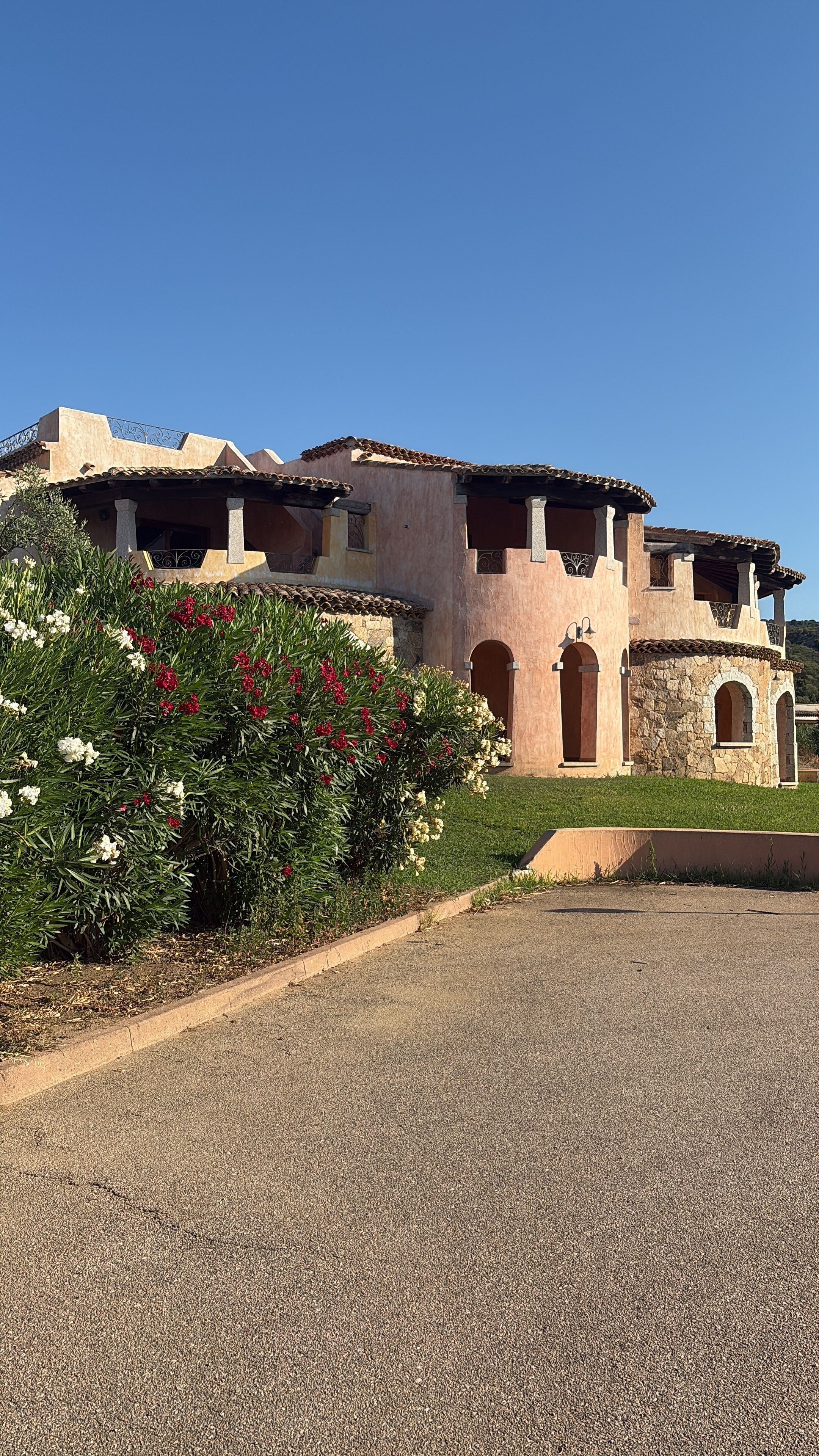 A large, multi-story building with a stucco exterior and terracotta roof tiles.