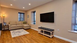 Un salon moderne avec un canapé beige, un téléviseur à écran plat fixé au mur et un banc en bois.