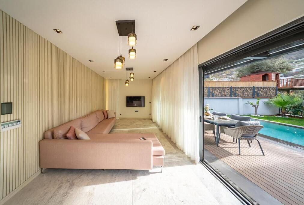 Una sala de estar moderna con un sofá, una mesa de comedor con sillas y vistas a una piscina.