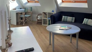 En moderne stue med højt til loftet, ovenlys, en sofa, et bord og en reol.