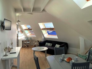 Ein moderner Loft-Raum mit Essbereich, einer Couch und zwei Oberlichtern, die einen Blick auf die Stadt bieten.