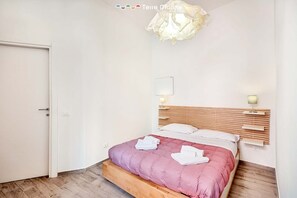A neatly arranged bedroom with a wooden bed frame, a bedside table with a lamp, and a wall-mounted light fixture. - Located in the heart of Riomaggiore, Il Palombaro will welcome you to offer you moments of relax with its furnished terrace ideal for outdoor breakfasts, romantic dinners under the stars or simply to enjoy a glass of wine. Inside you will find the kitche (Riomaggiore)