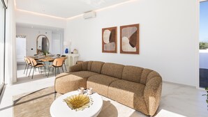 Een moderne woonkamer met een hoekbank, een eethoek met een tafel en stoelen, en twee abstracte schilderijen aan de muur.