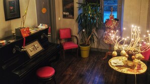 A cozy living room with a piano, a red chair, a potted plant, and a decorative table. - Onigourmand (Oloron-Sainte-Marie)