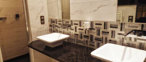 Une salle de bain moderne avec deux lavabos, un miroir et un mur recouvert de carreaux.