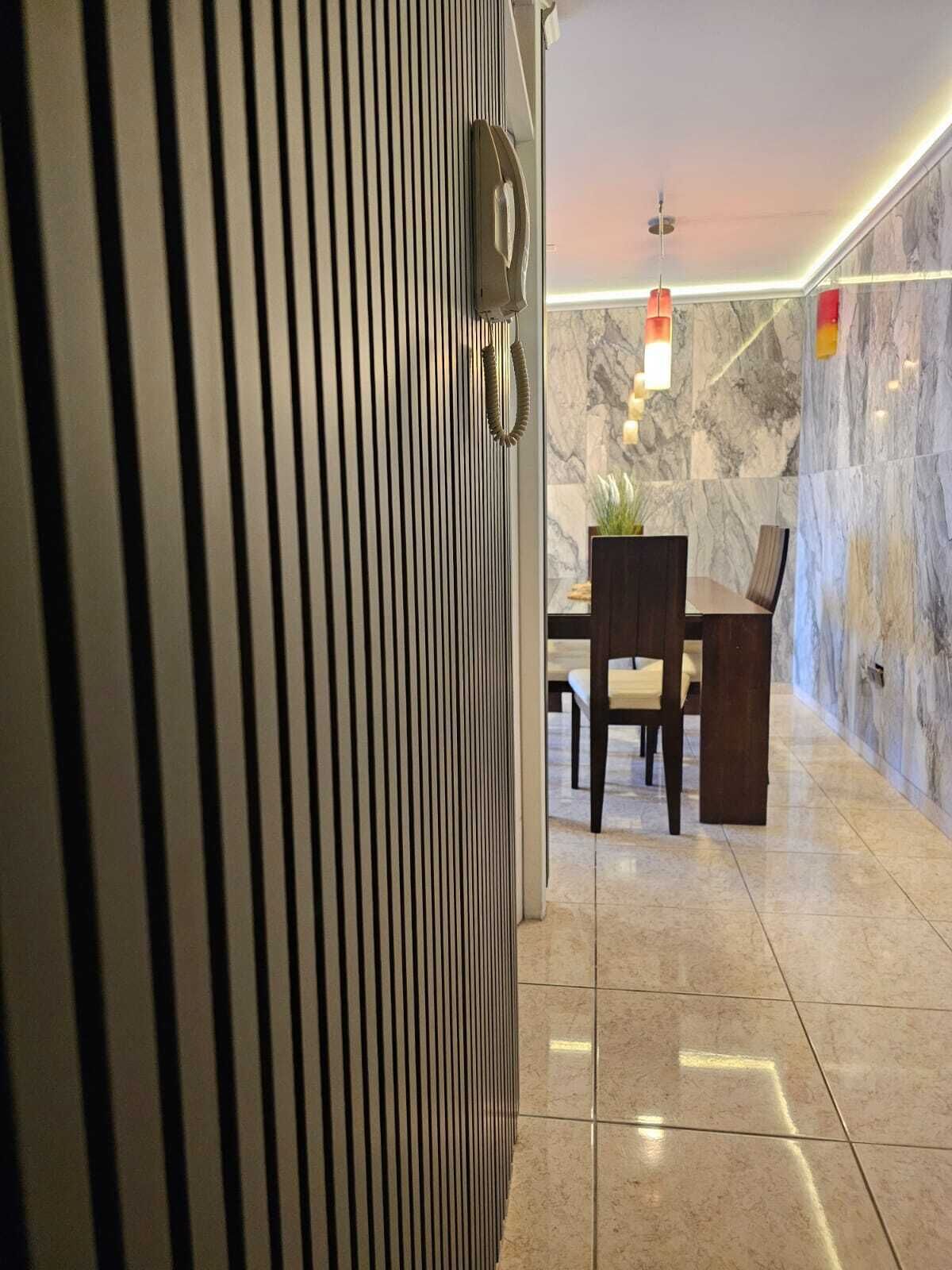 En modern hotellobby med en vägg av marmor, en receptionsdisk och en sittgrupp.