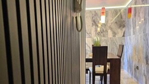 Una hall d'hotel moderna con una parete in marmo, una reception e un'area salotto.