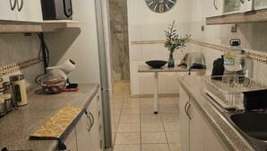 Una cucina con mobili bianchi, un forno a microonde, una sveglia e un lavello.