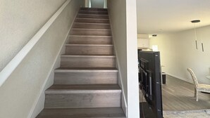 A staircase with a handrail, leading to a landing with a flat ceiling and a light fixture. - Cozy Modern Retreat, Peaceful Stay Near Everything (Portsmouth)
