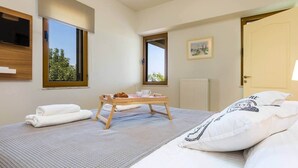 Et moderne hotelværelse med seng, et lille træbord med morgenmad, et vindue og en dør.