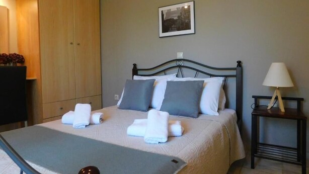 A neatly made bed with pillows and towels, a bedside table with a lamp, and a wardrobe.