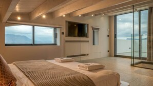 Een slaapkamer met een bed, een televisie, een groot raam en een balkon met uitzicht.