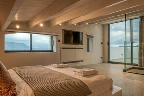 A bedroom with a bed, a TV, a large window, and a balcony with a view. - Villa Phos, Sea view, Luxury, private pool, BBQ (Τοπική Κοινότητα Καλλεργιανών)