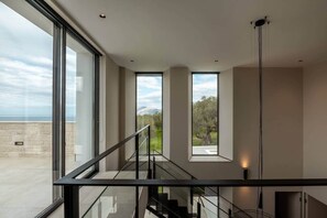 A modern interior with large windows, a staircase, and a view of the outdoors. - Villa Phos, Sea view, Luxury, private pool, BBQ (Τοπική Κοινότητα Καλλεργιανών)