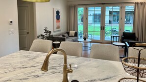 A modern living room with a marble dining table, a gold pendant light, and a view of the outdoor patio. - 2-bedroom villa in tranquil Provo with refreshing AC (Provo)