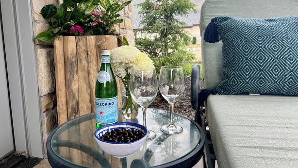 A glass table with a bottle of Pellegrino water, two wine glasses, and a bowl of olives. - 2-bedroom villa in tranquil Provo with refreshing AC (Provo)