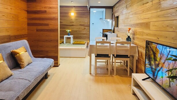 A modern living room with a sofa, dining table, and TV.