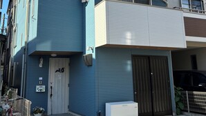 A multi-story residential building with a blue exterior, a white upper section, and a garage door.