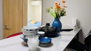 A kitchen counter with a blue vase of flowers, a coffee maker, and stacked plates and bowls.