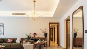 A dining area with a chandelier, a sofa, and a mirror. - Stylish 3BR Serviced Apart At Cairo Festival City (Cairo Governorate)