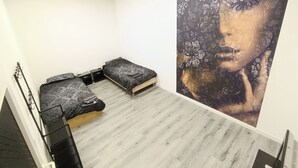 Une chambre avec deux lits, une grande œuvre d’art aux motifs floraux accrochée au mur et un plancher en bois.