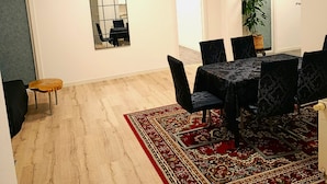 Une salle de conférence avec une table ronde, des chaises noires, un tapis rouge à motifs, une plante en pot et une œuvre d’art encadrée au mur.