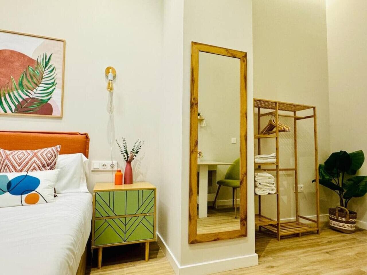 Un dormitorio con cama, mesita de noche, espejo y armario.