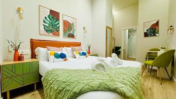 Una habitación de hotel moderna con una cama grande, detalles en verde y obras de arte en las paredes.