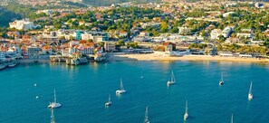 Ilmakuva rannikkokaupungista, jossa näkyy satama, rakennuksia ja ranta.