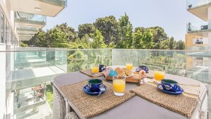 Een balkon met ontbijt, inclusief croissants, sinaasappelsap en koffiekopjes.