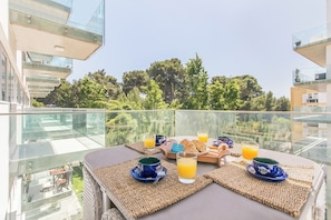 Ein Balkon mit Frühstücksangebot, darunter Croissants, Orangensaft und Kaffeetassen.