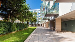 Een modern gebouw met een betegeld pad, groenvoorziening en een heldere lucht.