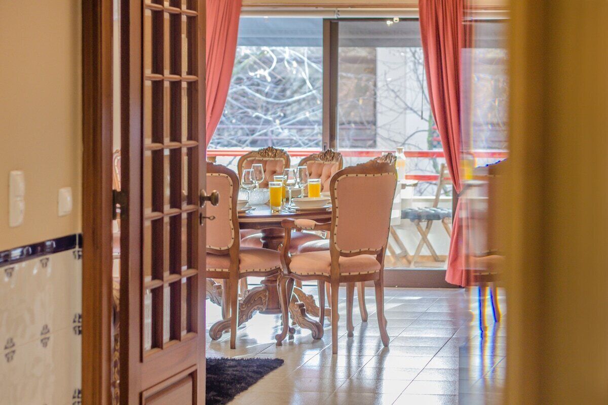 An open door leading to a dining area with a table set for four, chairs, and a view of the outdoors.