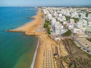 Eine Vogelperspektive einer Küstenstadt mit Strand, Gebäuden und einer Eisenbahnstrecke.