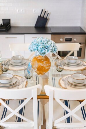 A dining table set with plates, glasses, and a vase with flowers. - BnBird Exclusive Oasis in Vilamoura (Quarteira)