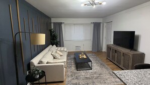 Un salon moderne comprenant un canapé, une table basse, un téléviseur et un coin repas.