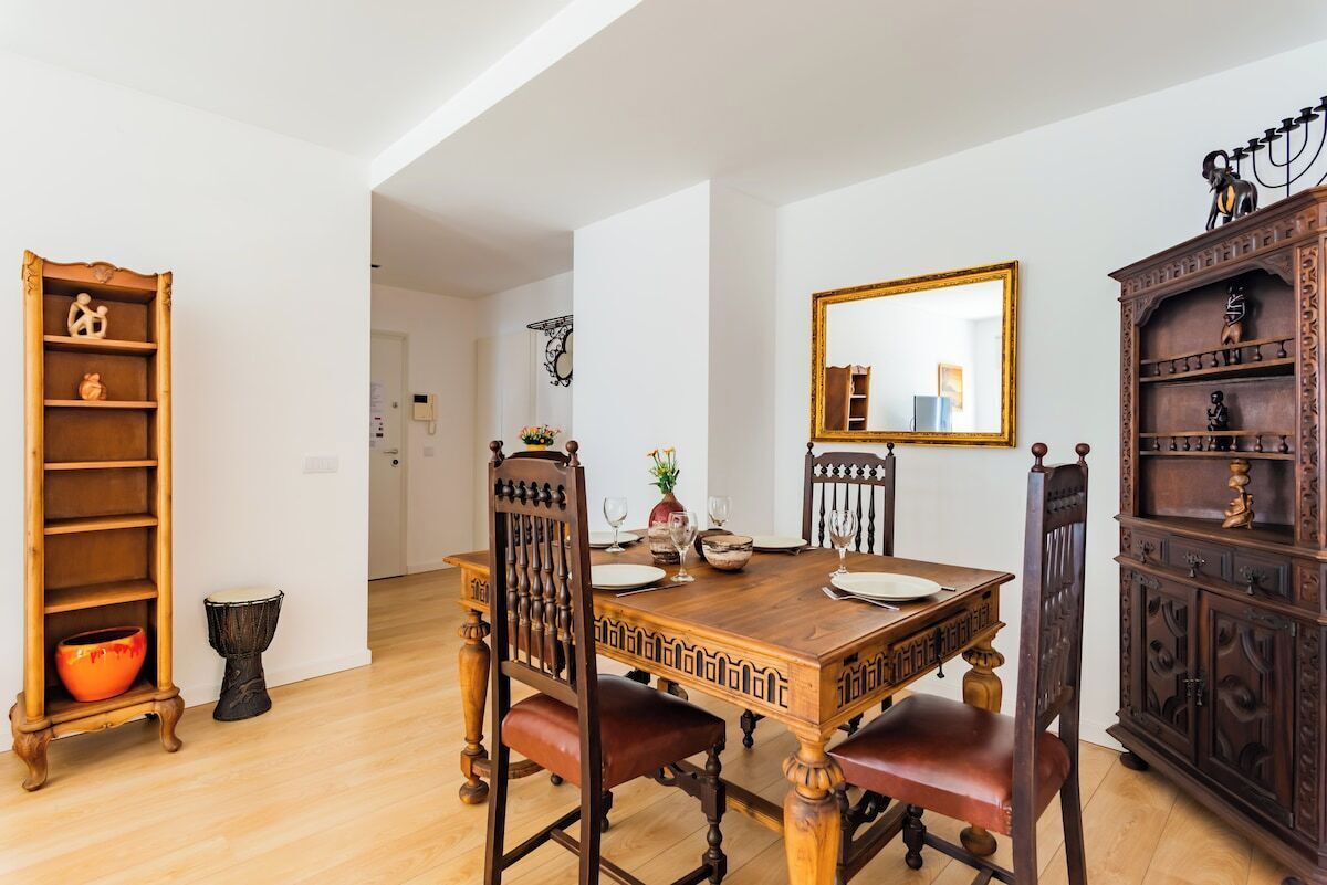 A dining area with a wooden table, chairs, a mirror, and a cabinet.