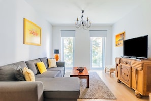 Ein Wohnzimmer mit einer Couch, einem Couchtisch, einem Fernseher und einem Holzschrank.