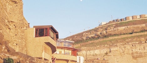 A hotel with a balcony overlooking a rocky landscape, a clear sky, and a distant moon.