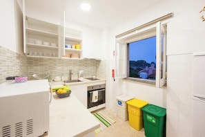 A kitchen with a window, white cabinets, a sink, and a trash bin. - Sintra Farm Villa Guest House (Sintra)