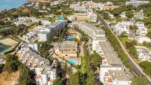 Vista aèria d'una zona residencial costanera amb edificis moderns, una piscina i una carretera.
